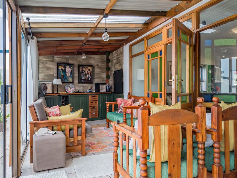 A covered patio area featuring a timber-framed roof, translucent panels, built-in cabinetry, and sliding glass doors, providing a versatile indoor-outdoor living space.