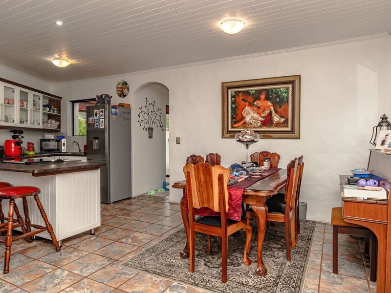Open plan kitchen and dining area featuring tiled flooring, a kitchen island with breakfast bar, and a distinctive tongue and groove ceiling.