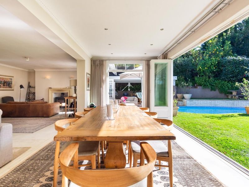 Spacious open-plan living and dining area featuring a fireplace and seamless indoor-outdoor flow through large stacking glass doors to the pool and garden.