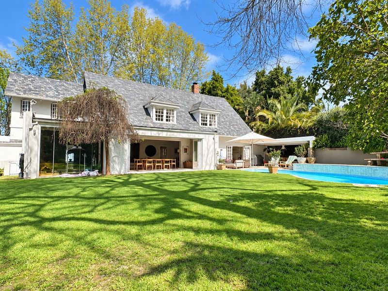 Rear view of a charming residence featuring a slate roof, dormer windows, a swimming pool, and a spacious lawn area.