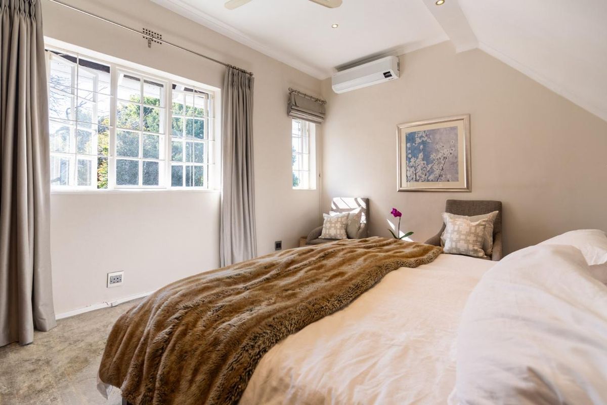 A well-maintained bedroom featuring a split-system air conditioner, recessed downlighting, and multi-pane windows with neutral finishes.