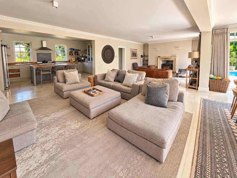 Spacious open-plan living area featuring a modern kitchen with island, comfortable lounge space, and a cozy fireplace, seamlessly flowing to the outdoor patio.