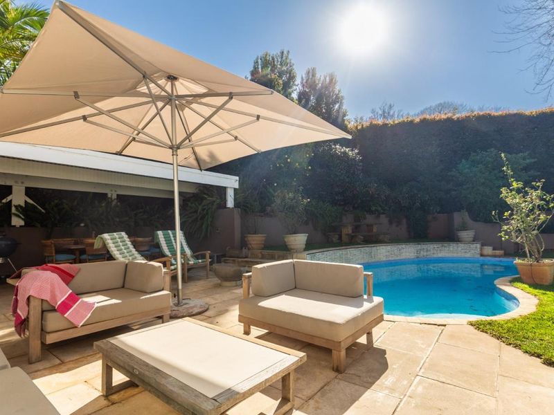 Outdoor entertainment area featuring a swimming pool, paved patio, and a covered seating space, ideal for relaxation and hosting.