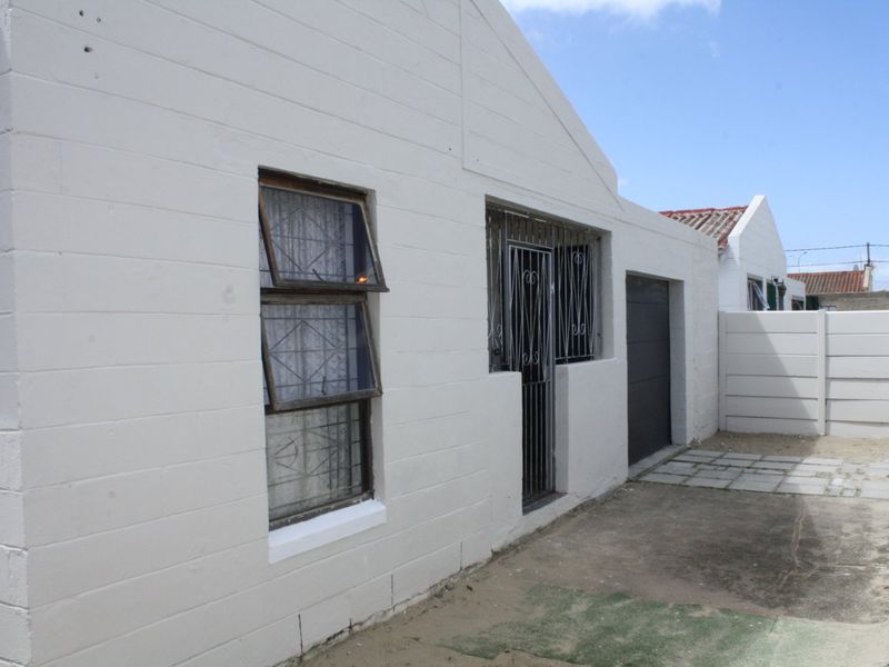 Front exterior view of the property featuring a paved driveway, garage access, and security-fitted windows and doors.