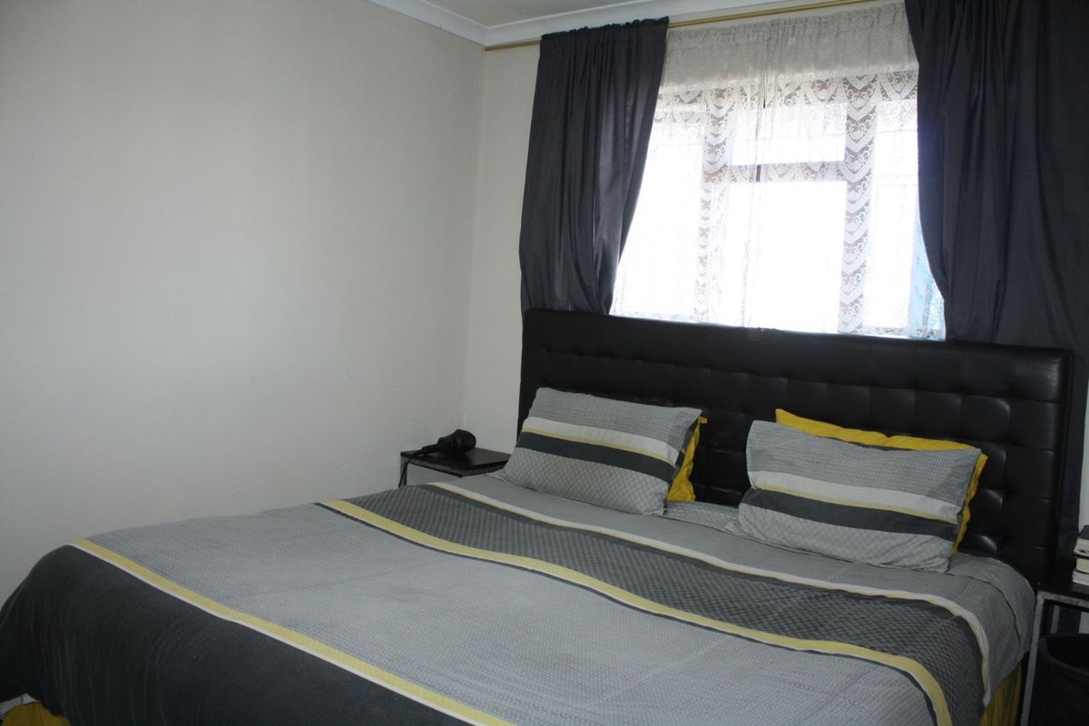 A standard bedroom featuring neutral wall finishes and a window with curtain tracks.