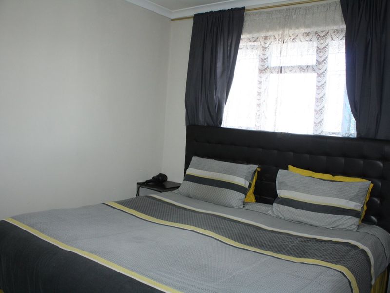 A standard bedroom featuring neutral wall finishes and a window with curtain tracks.