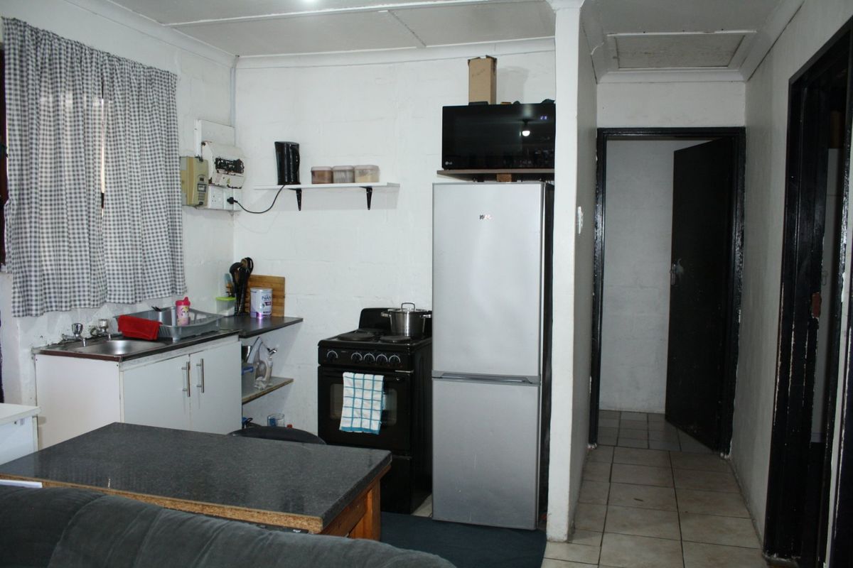 Compact kitchen area featuring basic cabinetry, a freestanding stove, and tiled flooring, offering potential for modernization and improved layout efficiency.