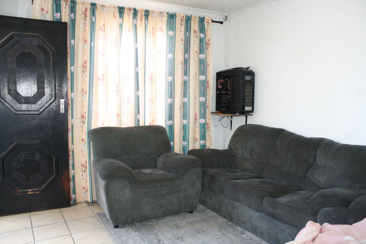 A living room featuring tiled flooring and coved ceilings, providing a functional space with potential for modern updates.