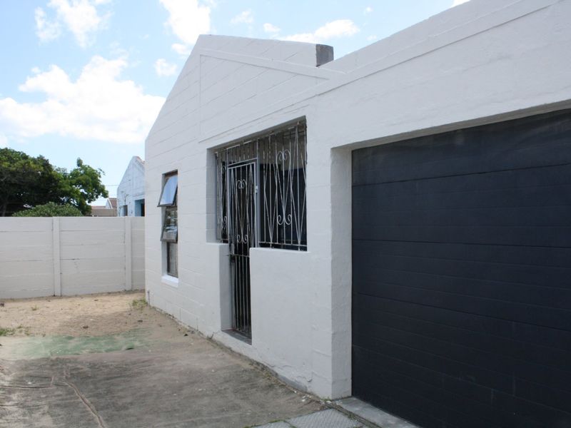 Front exterior view of the property featuring a garage, security gates, and a concrete driveway enclosed by a precast boundary wall.