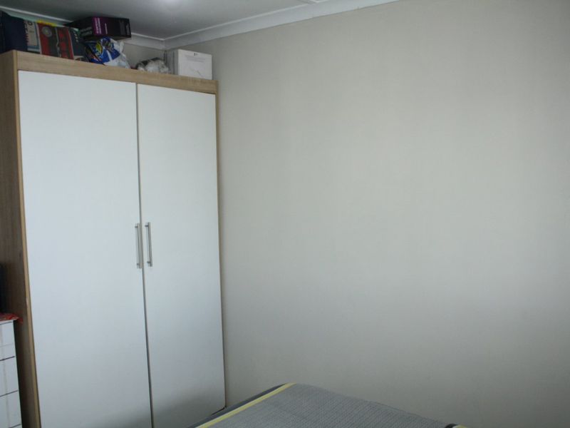 A bedroom featuring a built-in wardrobe with white doors and wood-effect frame, finished with simple coving.