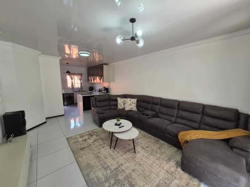 Open-plan living area featuring glossy tiled flooring, a modern ceiling finish, and a functional kitchen with integrated cabinetry and island.