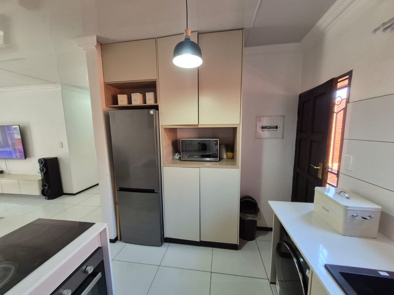 Modern kitchen area featuring built-in cabinetry, integrated microwave, electric hob, and oven, with tiled flooring and open-plan access to the living space.