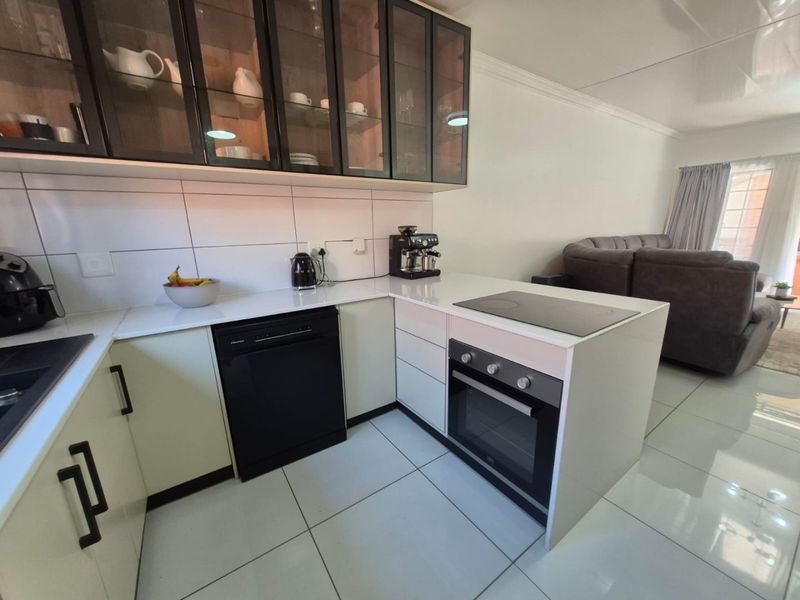 Modern open-plan kitchen featuring sleek cabinetry, integrated appliances, and tiled flooring, seamlessly flowing into the adjacent living area.