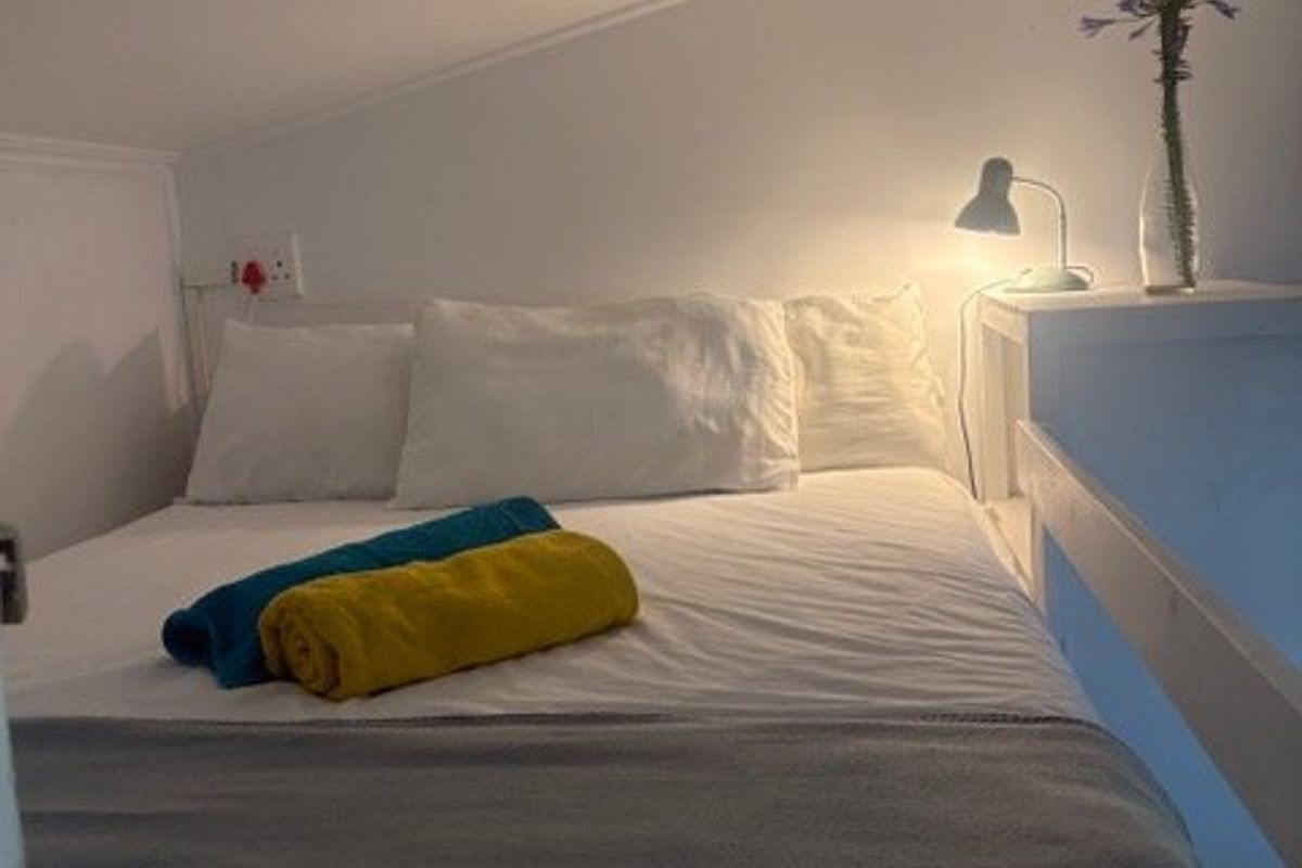 A cozy loft-style bedroom featuring a sloped ceiling and compact sleeping area.