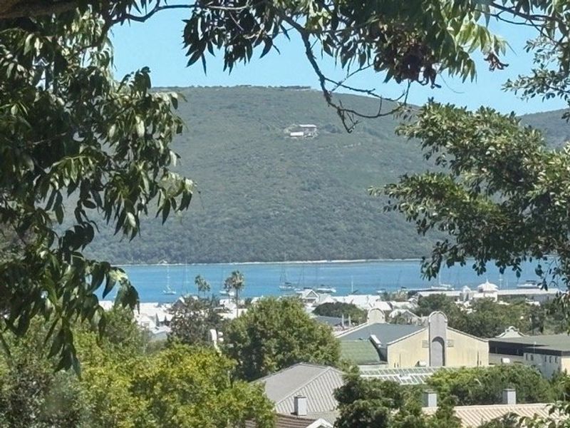 A scenic elevated view overlooking the bay, surrounding residential rooftops, and the distant mountain landscape.
