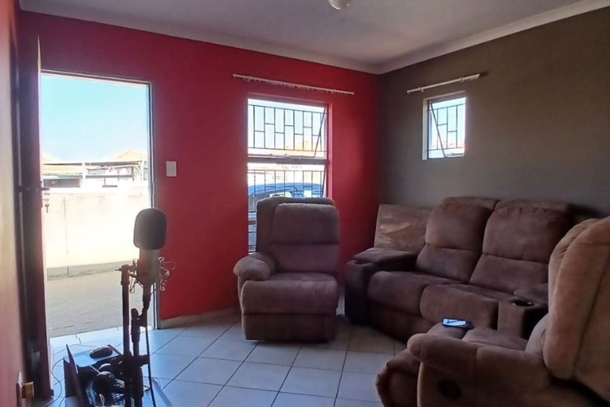A living room featuring tiled flooring and security bars on the windows, with a dual-tone wall finish.