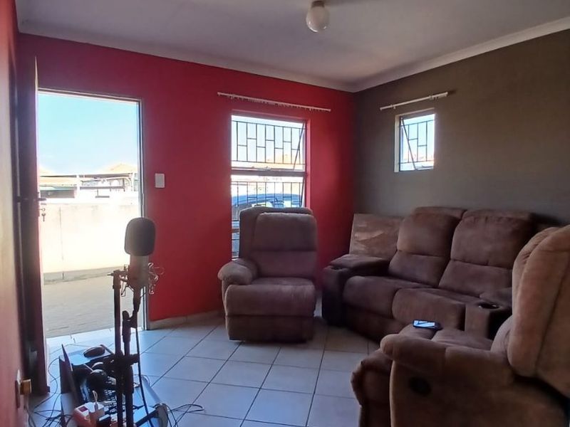 A living room featuring tiled flooring and security bars on the windows, with a dual-tone wall finish.