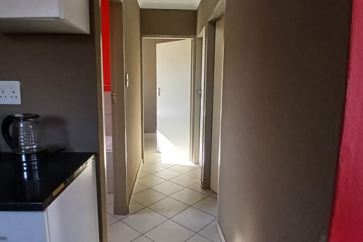 A functional hallway featuring tiled flooring and access to multiple rooms, connecting the kitchen area to the rest of the home.