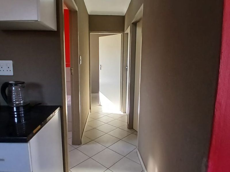 A functional hallway featuring tiled flooring and access to multiple rooms, connecting the kitchen area to the rest of the home.