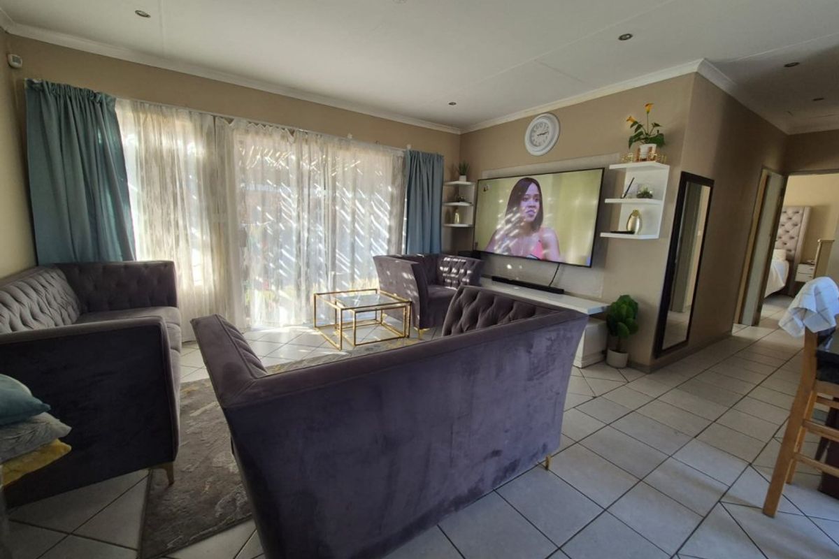 A comfortable living room featuring tiled flooring, recessed lighting, and large sliding glass doors that provide ample natural light.