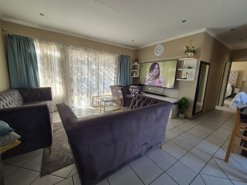 A comfortable living room featuring tiled flooring, recessed lighting, and large sliding glass doors that provide ample natural light.