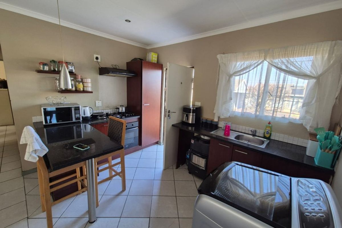 A functional kitchen featuring dark cabinetry, granite countertops, a breakfast nook, and tiled flooring, providing a practical layout for daily meal preparation.