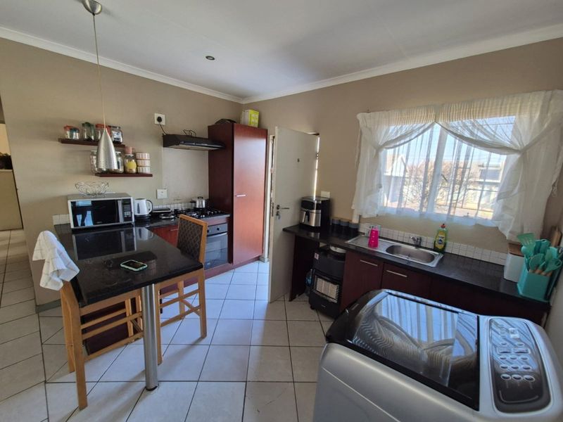 A functional kitchen featuring dark cabinetry, granite countertops, a breakfast nook, and tiled flooring, providing a practical layout for daily meal preparation.