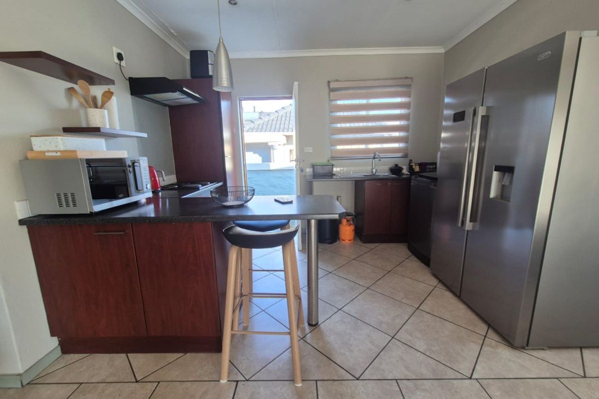 A functional kitchen featuring dark wood cabinetry, laminate countertops, tiled flooring, and direct access to the exterior.
