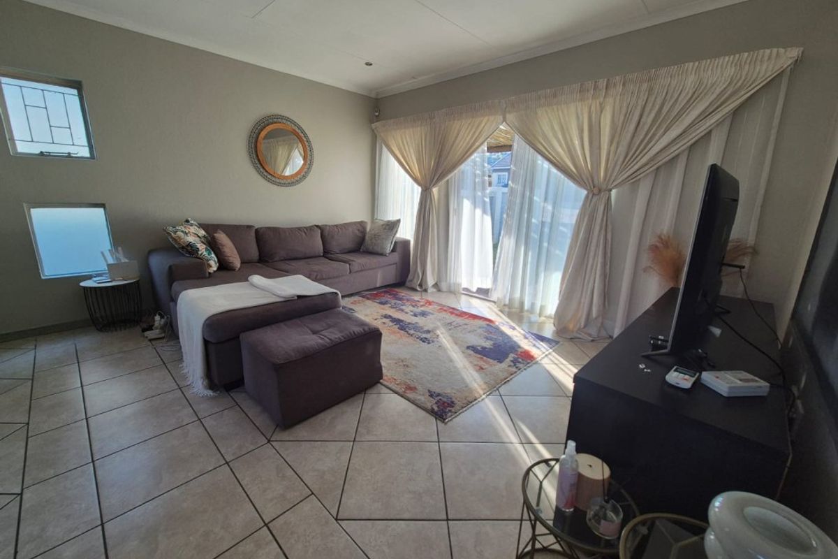 A comfortable living room featuring tiled flooring, recessed lighting, and a large sliding glass door providing access to the outdoor area.