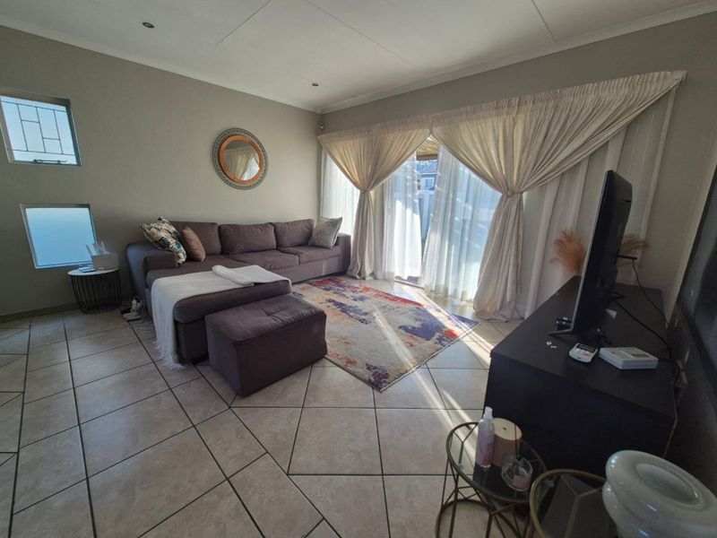 A comfortable living room featuring tiled flooring, recessed lighting, and a large sliding glass door providing access to the outdoor area.