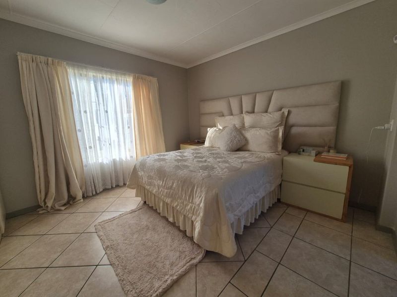 A well-maintained bedroom featuring neutral wall tones, tiled flooring, and a coved ceiling, providing a comfortable and functional living space.