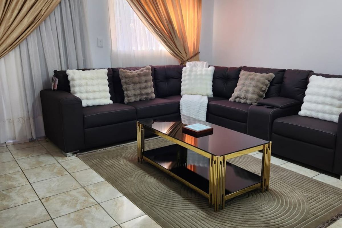 A living room featuring ceramic floor tiles, coved ceilings, and a fluorescent light fixture, providing a functional and neutral living space.