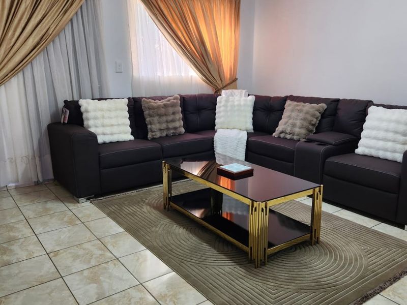 A living room featuring ceramic floor tiles, coved ceilings, and a fluorescent light fixture, providing a functional and neutral living space.