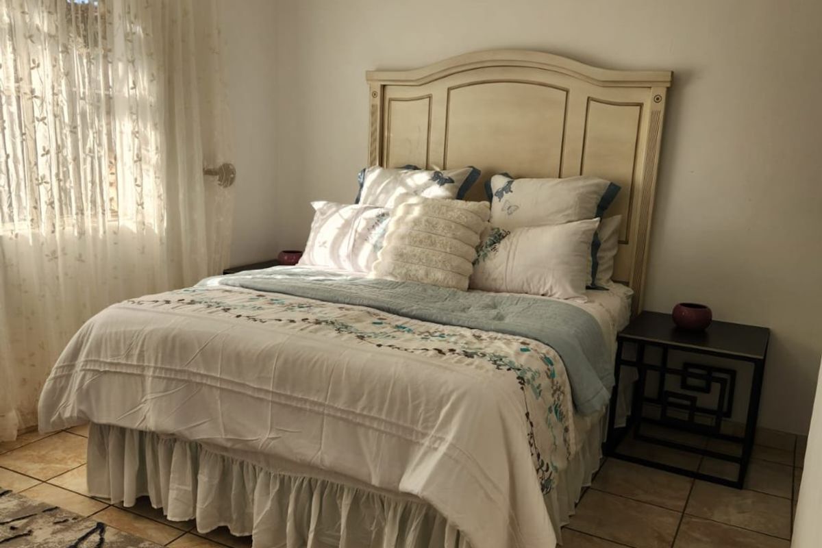A bedroom featuring tiled flooring, a ceiling fan, and natural light from a window.