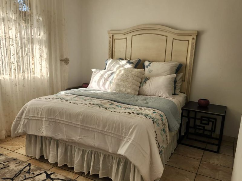 A bedroom featuring tiled flooring, a ceiling fan, and natural light from a window.