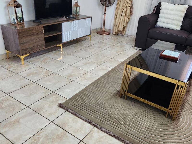 A living room featuring neutral ceramic floor tiles and window treatments, providing a functional and well-maintained space for relaxation.