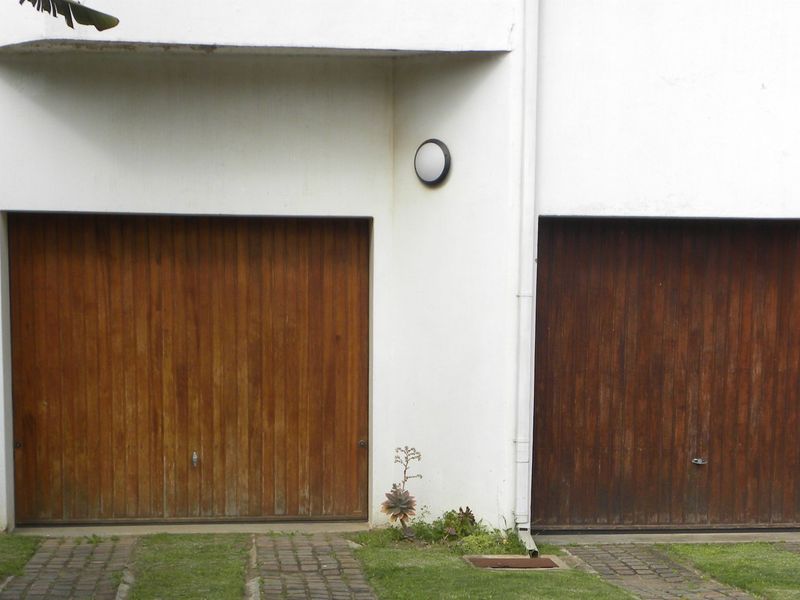 Exterior view of a double garage featuring timber doors and paved driveway access.