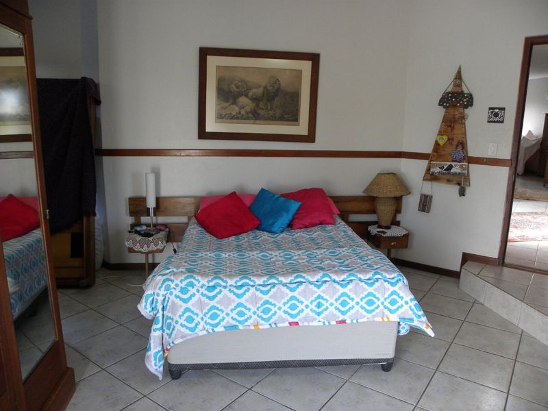 A bedroom featuring tiled flooring, a wooden dado rail, and a built-in headboard.