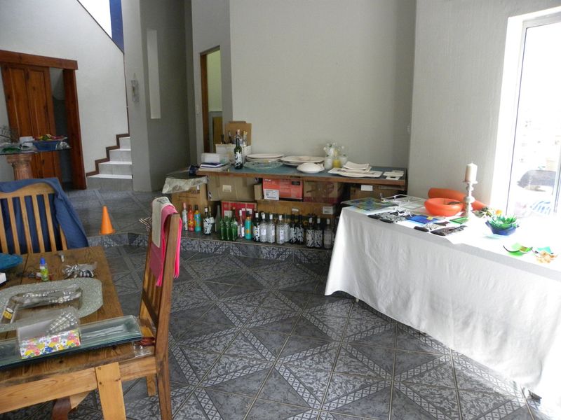 A living area featuring tiled flooring and an internal staircase, offering a functional space with potential for modern updates.