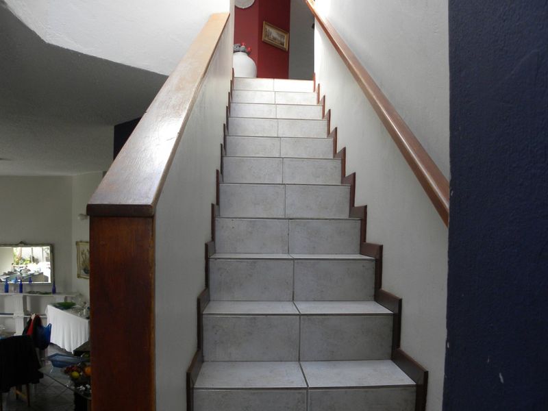 A staircase featuring tiled steps and a wooden handrail, providing access between levels within the home.