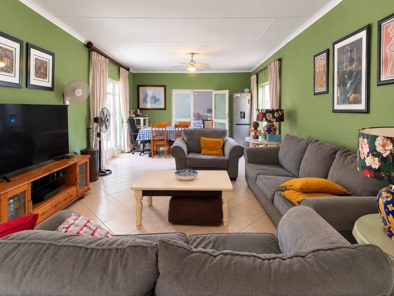 Spacious open-plan living and dining area featuring tiled flooring, a ceiling fan, and direct access to the outdoor space through double glass doors.