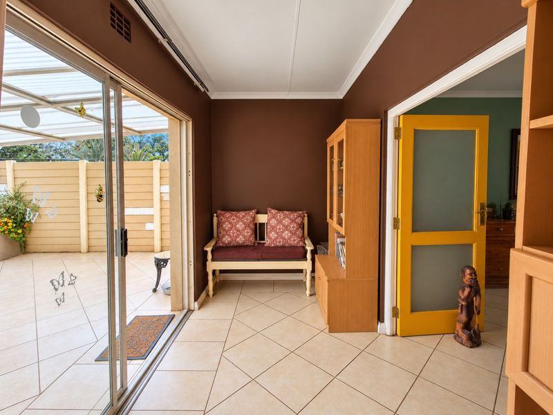 A sunroom or enclosed patio area featuring tiled flooring, a sliding glass door leading to an outdoor space, and a bright yellow interior door.
