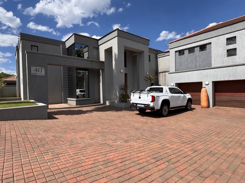 Modern double-story residential property featuring a spacious paved driveway and integrated double garage with wooden doors.