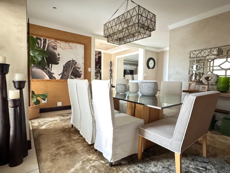 A well-appointed dining room featuring textured wall finishes, decorative pendant lighting, and large windows with venetian blinds, creating an elegant and inviting atmosphere.