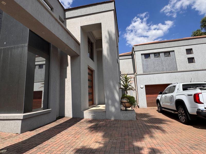 Modern architectural front facade featuring a paved driveway, recessed entrance, and integrated double garage.