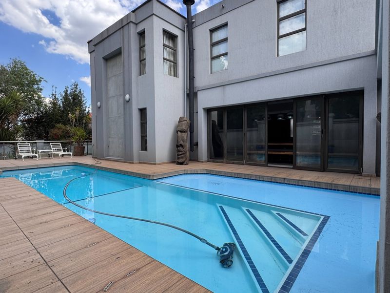 Modern outdoor pool area featuring composite decking, a well-maintained swimming pool, and large sliding glass doors providing seamless access to the home's interior.