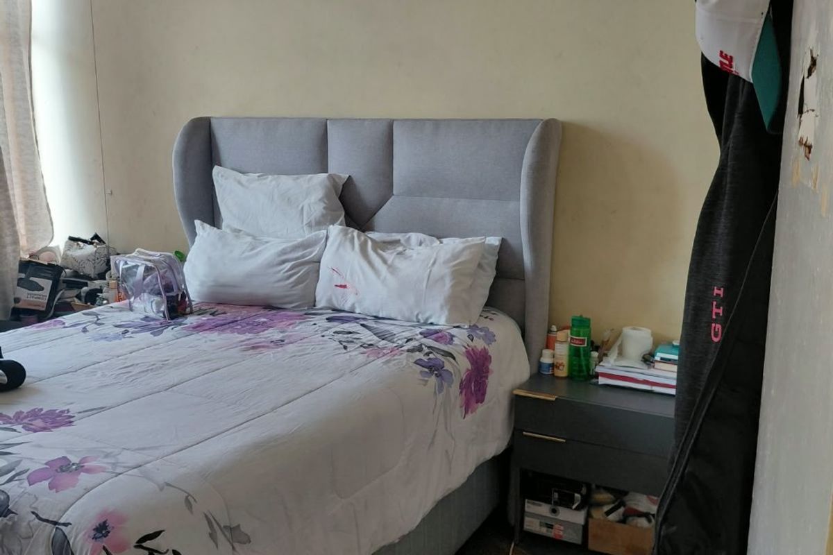 A bedroom featuring stone flooring and plain walls, currently requiring cosmetic updates and repairs to the wall finishes.