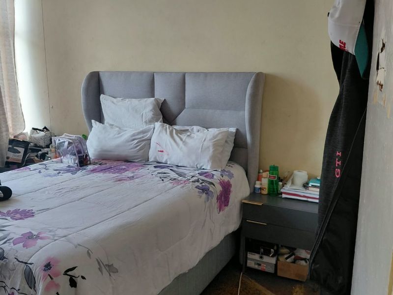 A bedroom featuring stone flooring and plain walls, currently requiring cosmetic updates and repairs to the wall finishes.