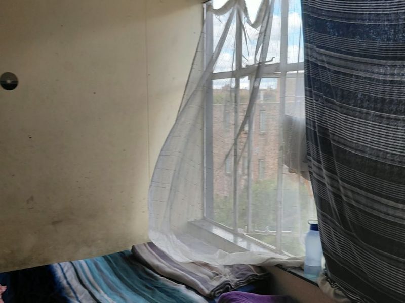 A bedroom featuring a large window with natural light, requiring cosmetic updates to the wall finishes to improve the overall condition.