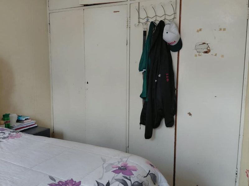 A bedroom featuring built-in cupboards with visible surface wear and paint damage, offering potential for cosmetic refurbishment.
